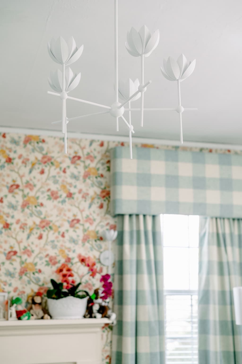 A blue upholstered chair beside a nursery window with soft curtains and natural light.