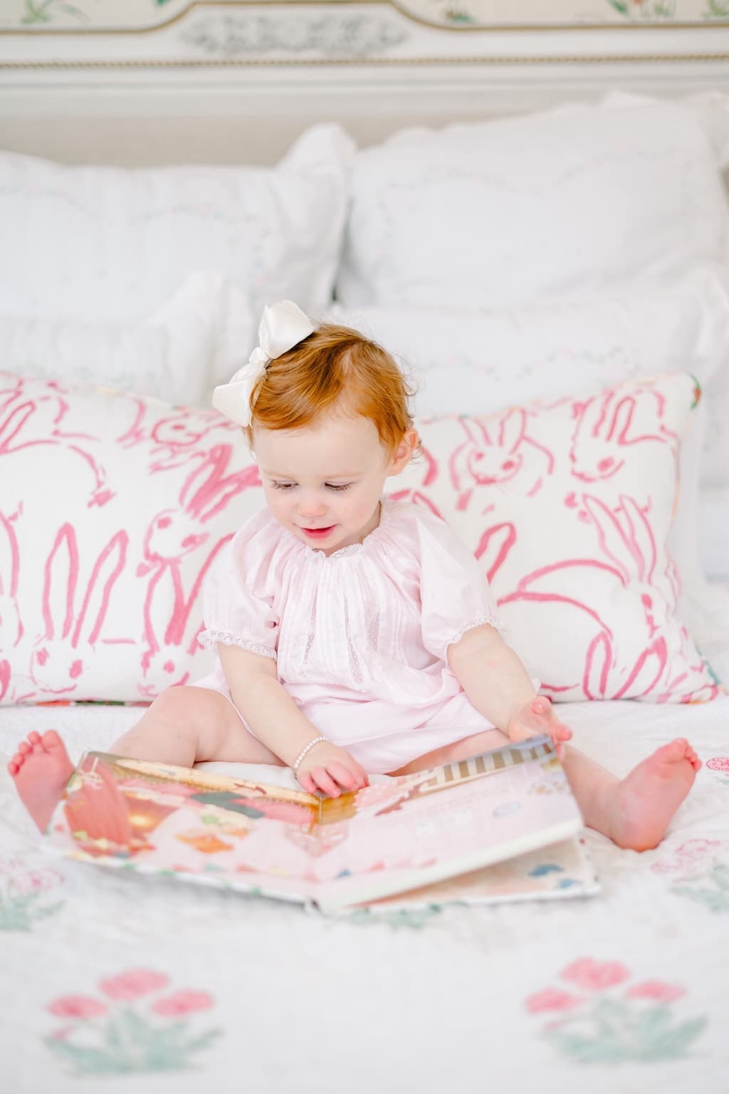 A nursery view with chandelier, upholstered stools, floral wallpaper, and layered furnishings.